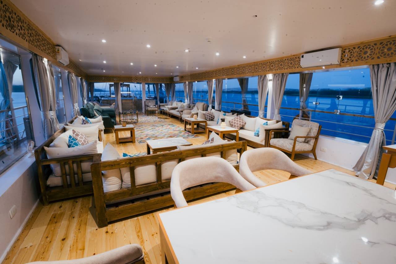 Luxurious indoor lounge and dining area of Soul of the Nile Dahabiya with marble tables and panoramic windows